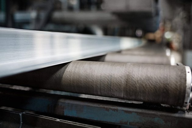 Extruded aluminium bar emerging from press on rollers