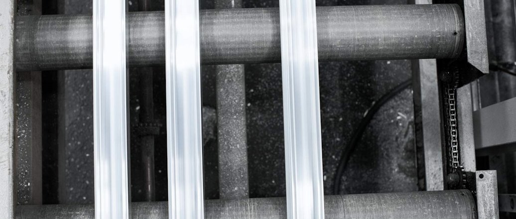 Overhead image of three pieces of extruded aluminum on rollers