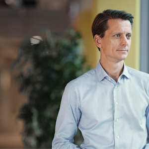 A person standing in front of an office window looking outside A person standing in front of an office window looking outside