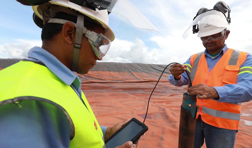a few men in hardhats looking at a piece of wood