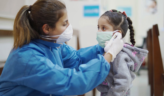 Women giving facemask to girl