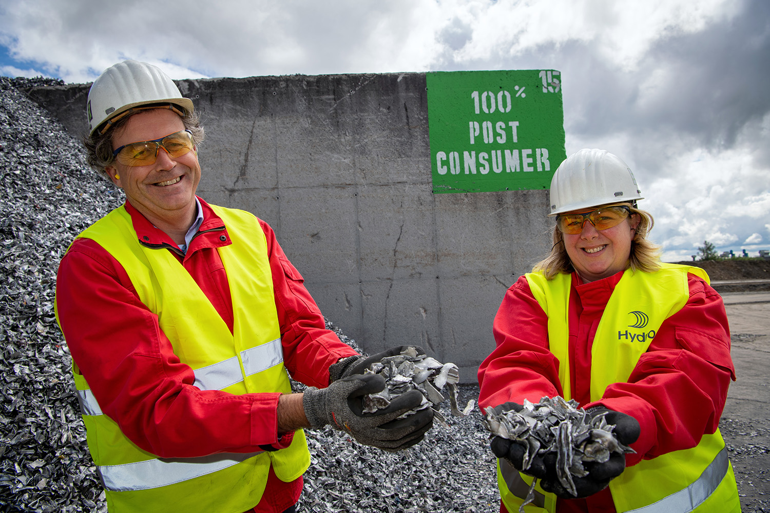 a man and woman wearing hard hats and holding aluminium scrap