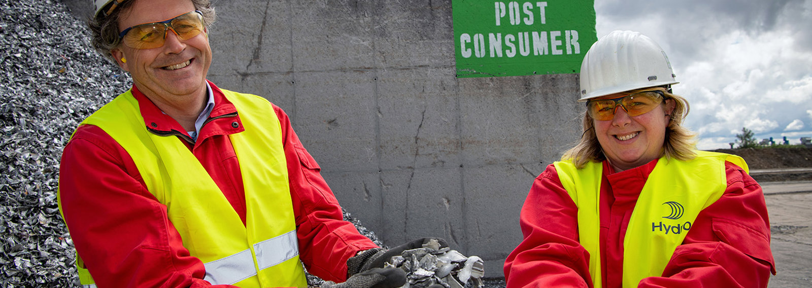 a man and woman wearing hard hats and holding aluminium scrap