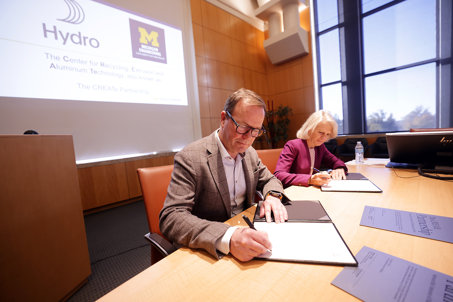 a man and a woman sitting at a table signing a paper
