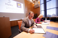 a man and a woman sitting at a table signing a paper