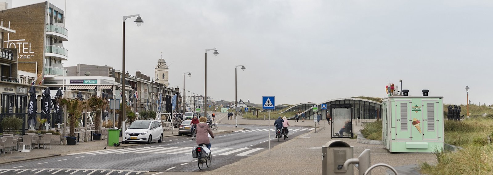 a person riding a bicycle on a road with buildings on either side