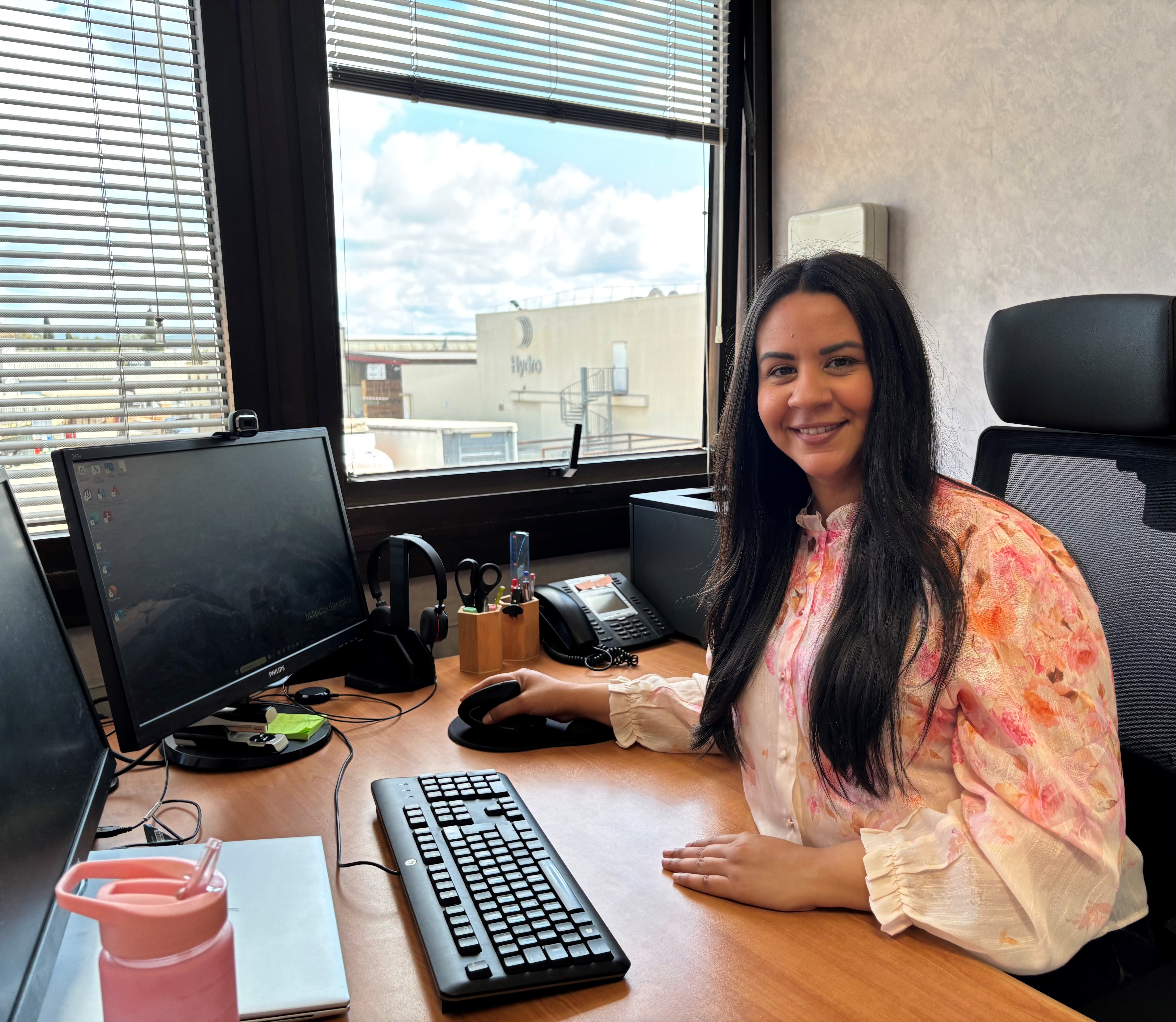 a person sitting at a desk with a computer and a window